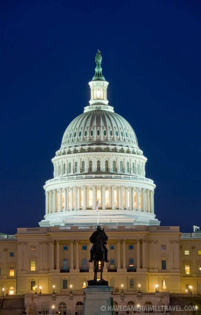 The United States Capitol building illuminated at night with a clear dark sky in the background, featuring a prominent dome and a statue at the top.