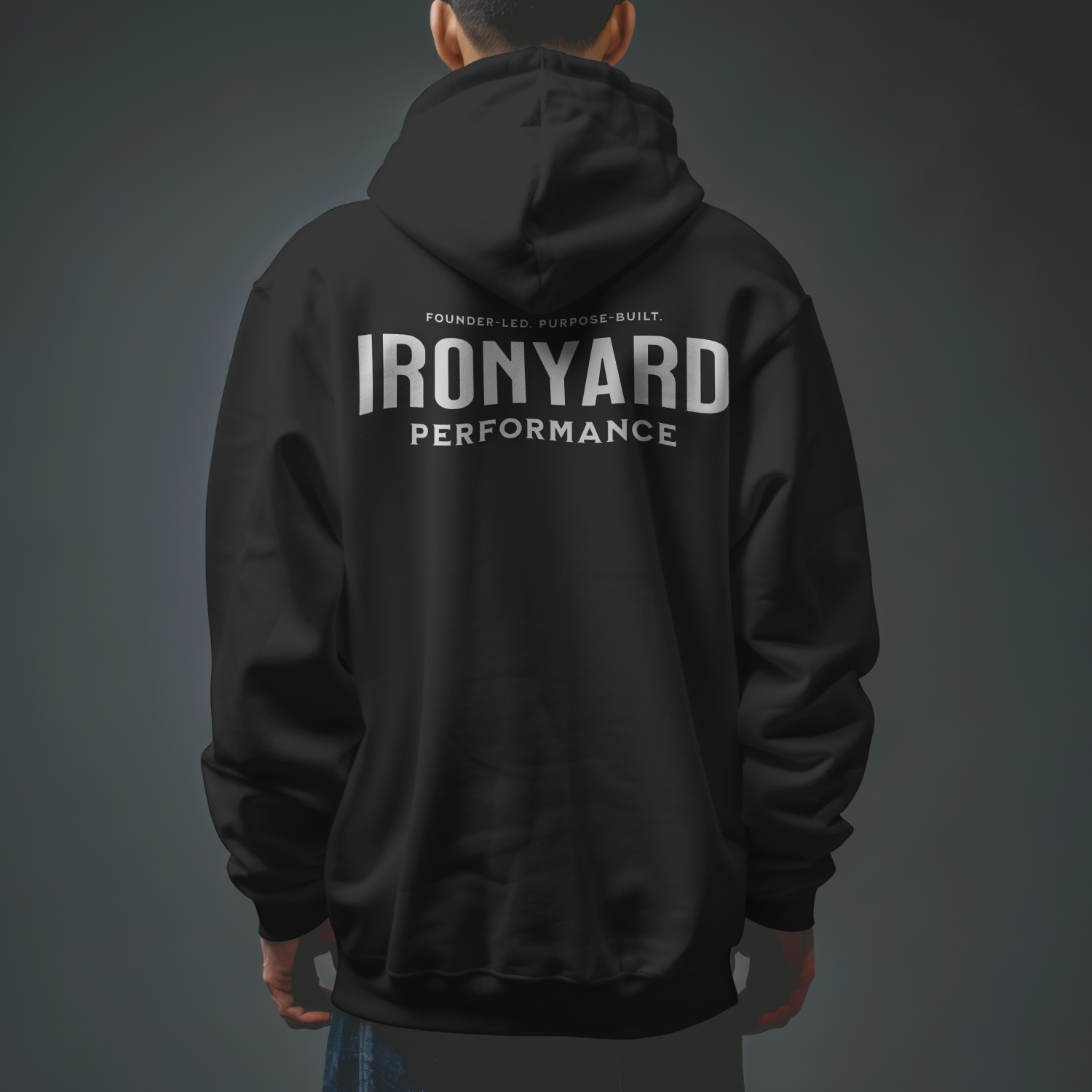 Back view of a person wearing a black jacket with large white text reading 'IRONYARD PERFORMANCE' on the back and smaller text above that says 'FOUNDER-LED. PURPOSE-BUILT.' The background is a plain, dark gradient.