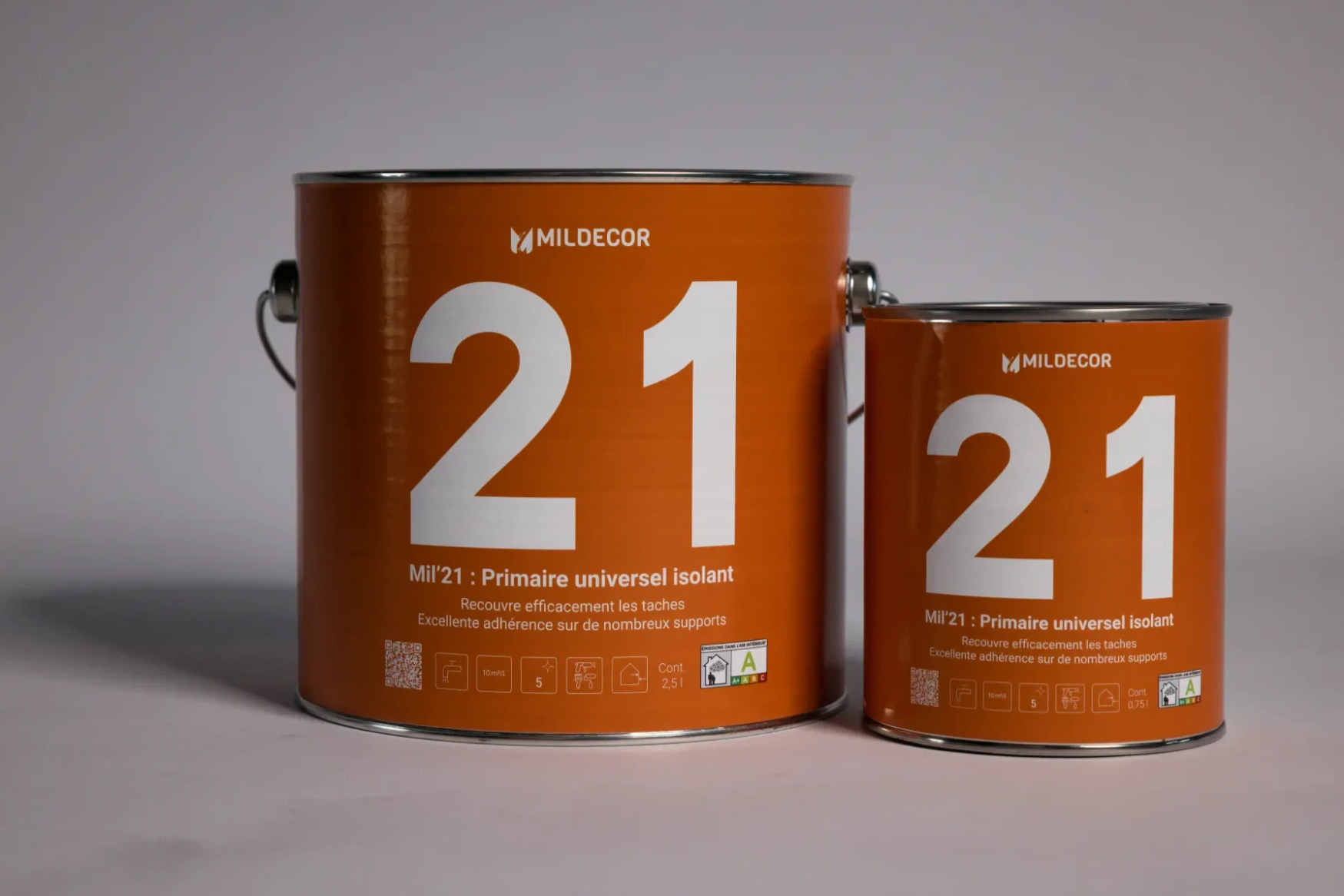 Deux bidons de peinture orange avec le texte '21' et 'Mildecor' visibles. Le plus grand bidon indique qu'il s'agit d'une peinture isolante universelle couvrant efficacement les taches et adhérant bien. Le plus petit bidon a une capacité de 0,75 litre, l'autre 2,5 litres.