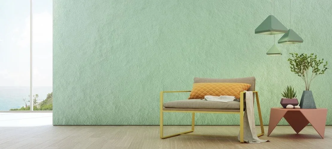 Salon moderne avec fauteuil, canapé, lampes suspendues, plante, et vue sur la mer à travers une grande fenêtre