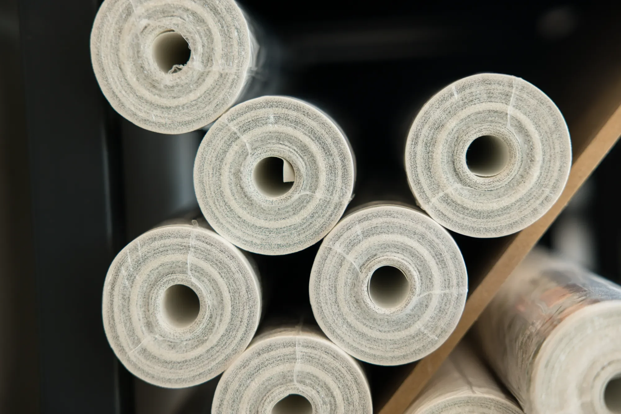 Rouleaux de papier ou de tissu empilés en cercle, vue de face, avec un fond sombre.