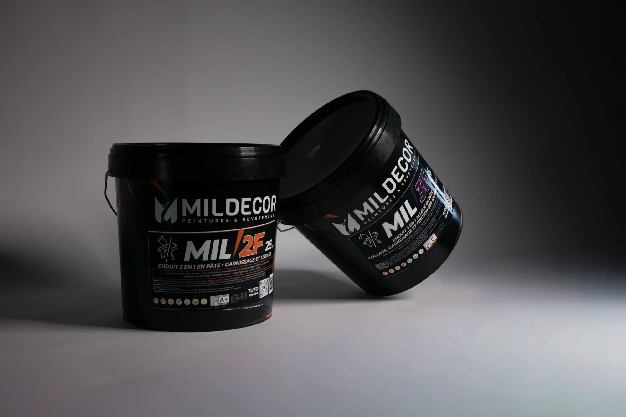 Deux pots de peinture noirs de la marque MILDECOR, un ouvert et l'autre fermé, sur un fond gris clair. 