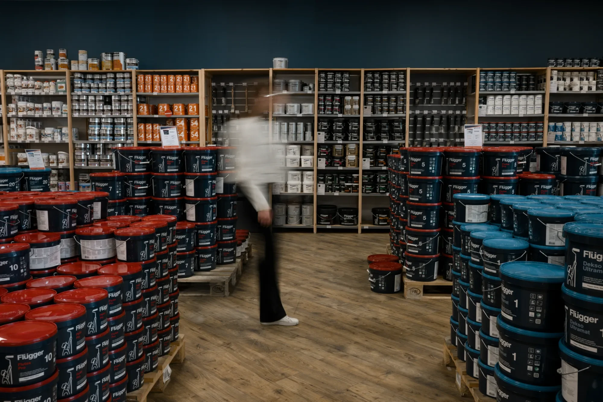 Intérieur d'une magasin de bricolage avec des étagères remplies de pots de peinture en différentes couleurs et tailles.