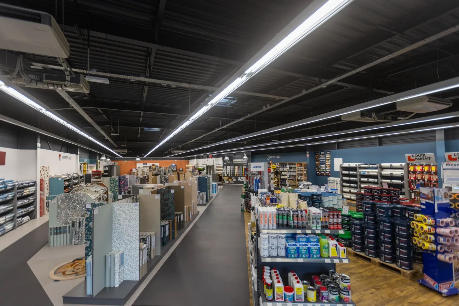 Intérieur d'un magasin de bricolage avec rayons de peinture, outils et matériaux de construction