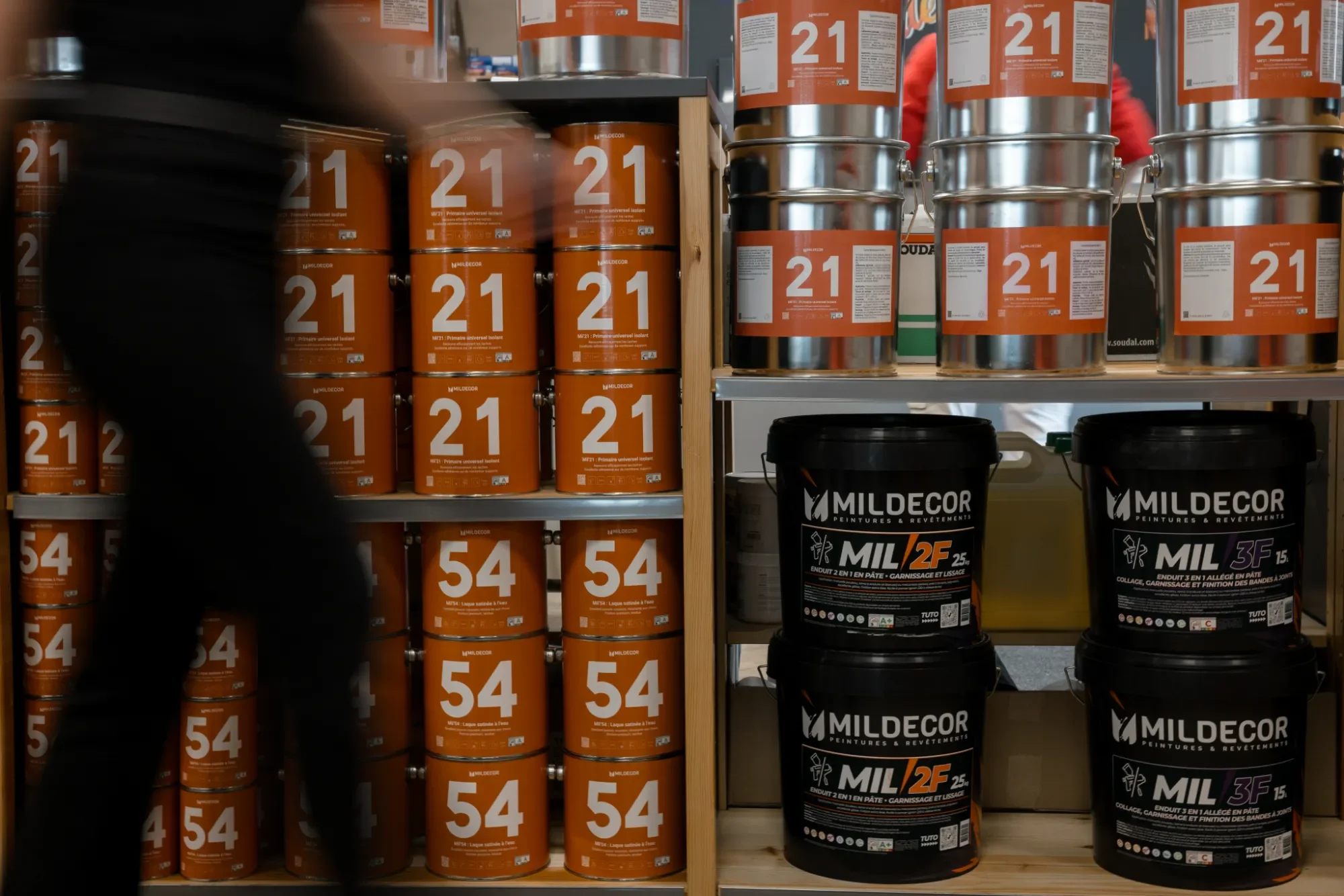 Étals d'exposition avec seaux de peinture orange et noirs dans un magasin de bricolage.