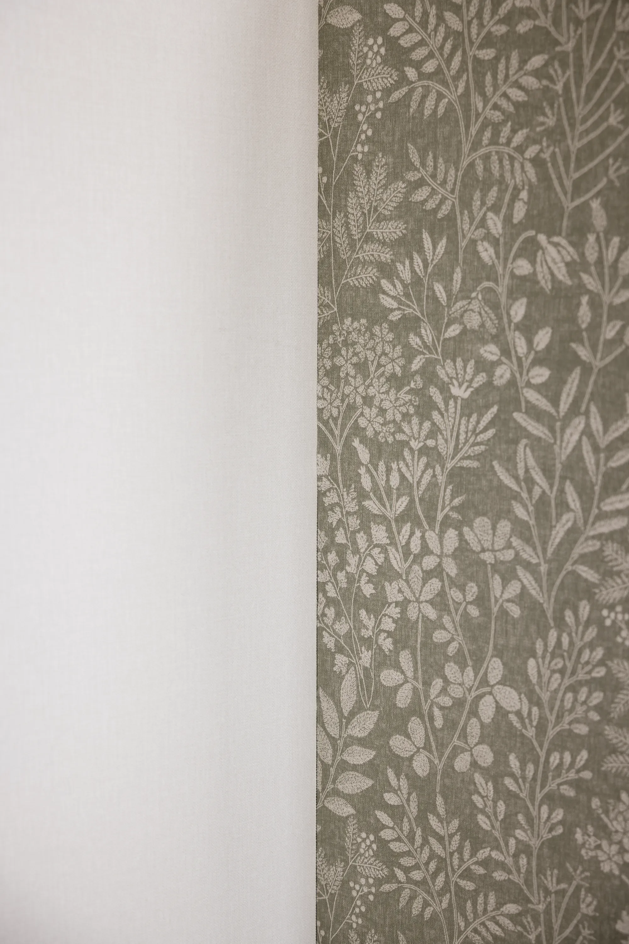 Photo de deux types de papier mural, l'un à motifs floraux et végétaux, l'autre blanc et unicolore.
