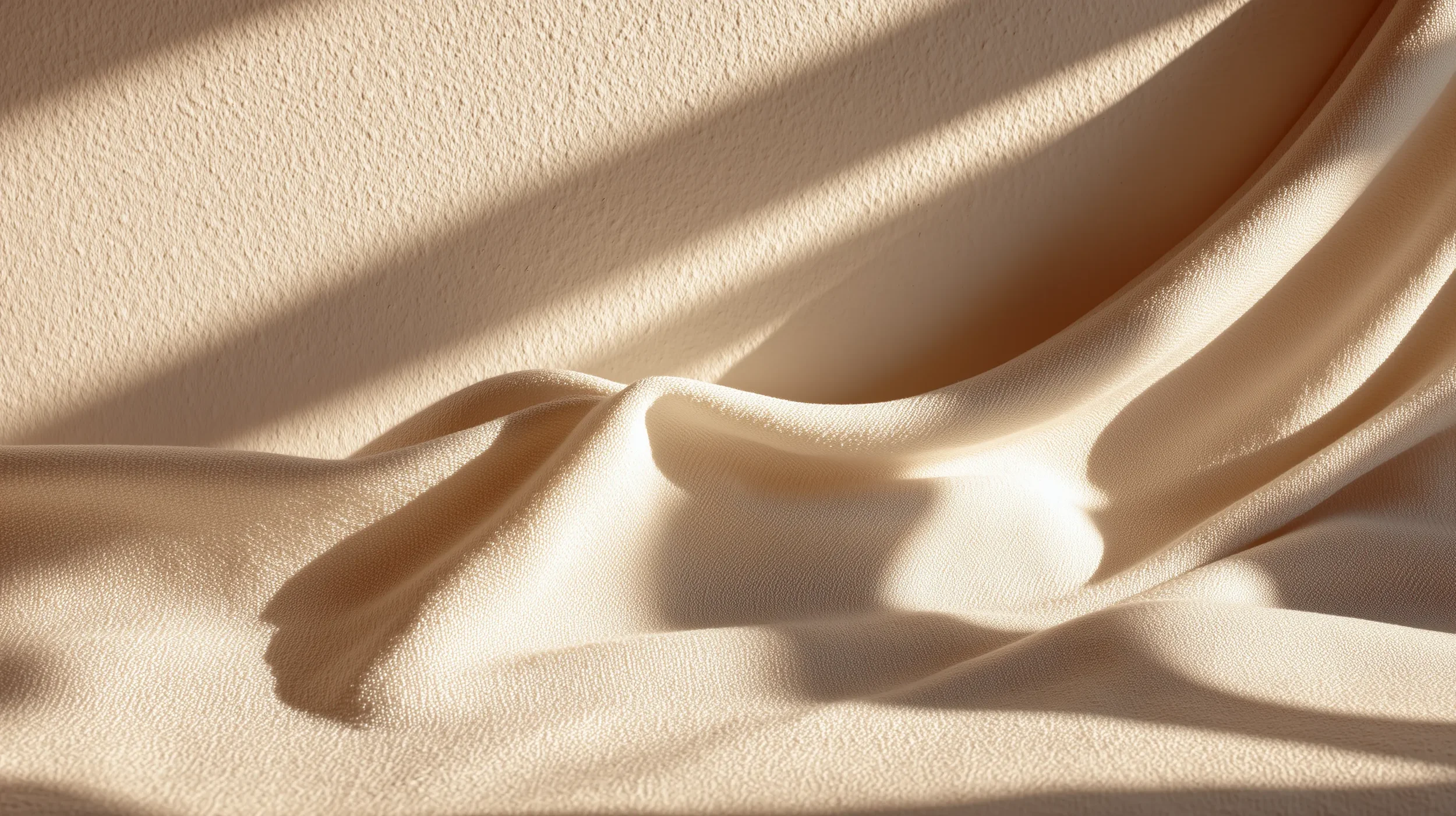 Cream-colored satin fabric draped with shadows cast by sunlight.