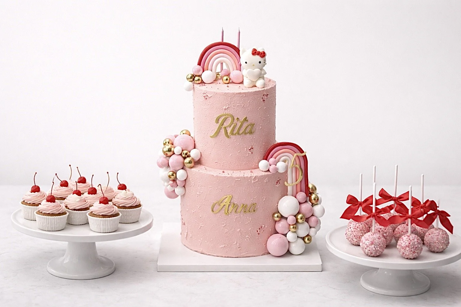 Pink themed birthday cake with topper, cupcakes with cherries, and cake pops with red ribbons on white cake stands.
