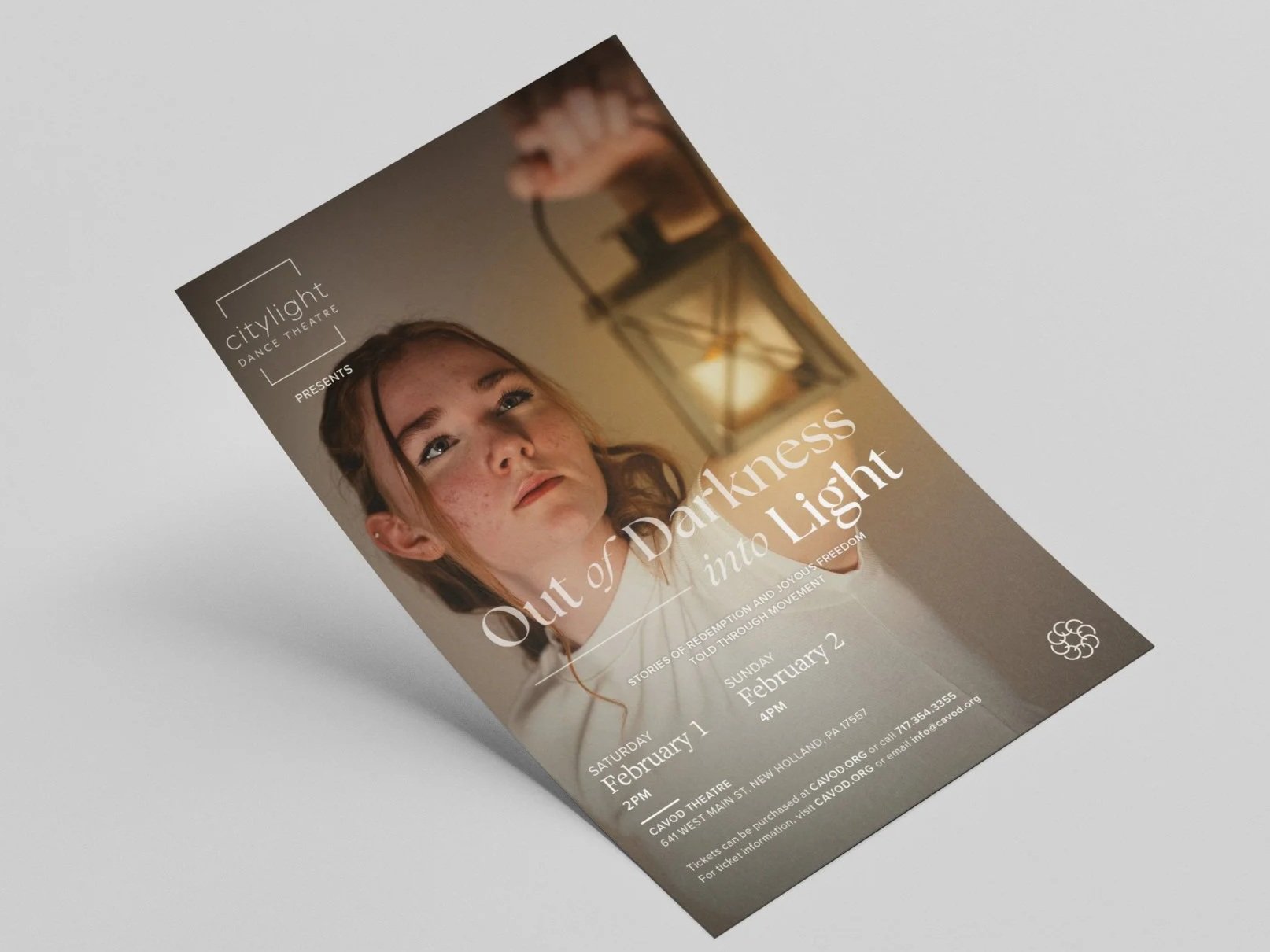 Out of Darkness into Light show flyer on tabletop. Depicts woman with lantern and show dates and information.