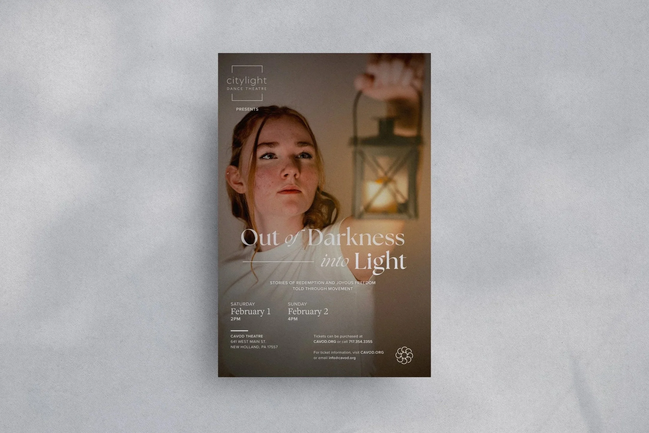 Out of Darkness into Light show poster on wall. Depicts woman with lantern and show dates and information.