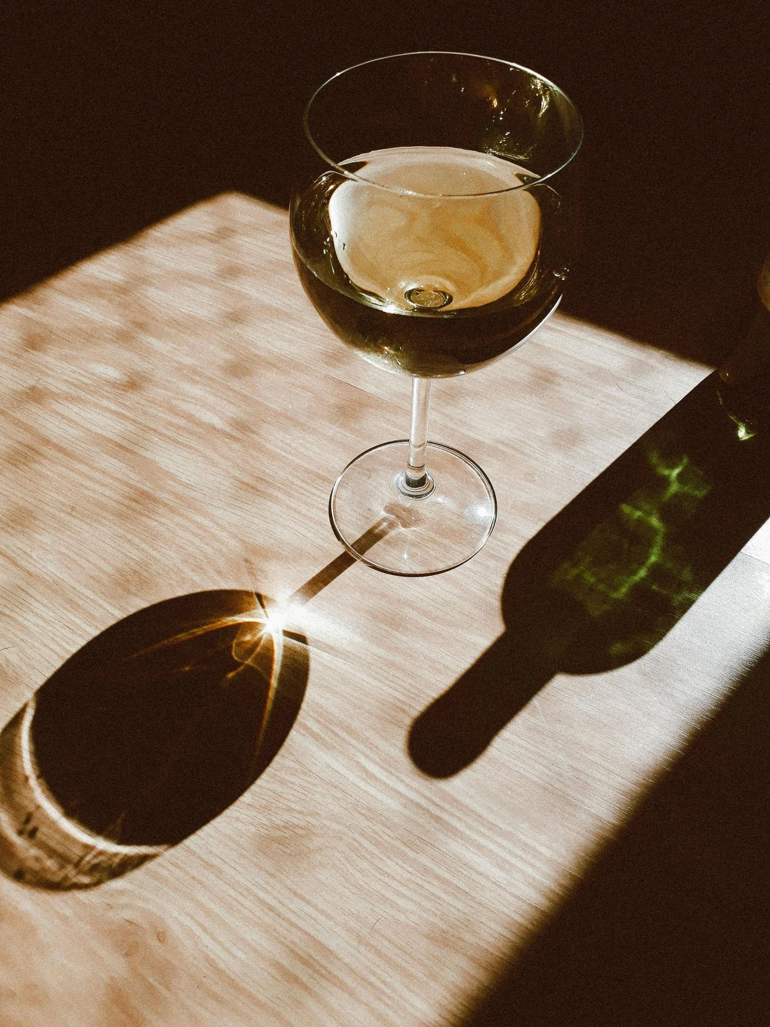 Glass of white wine on wooden table in natural sunlight