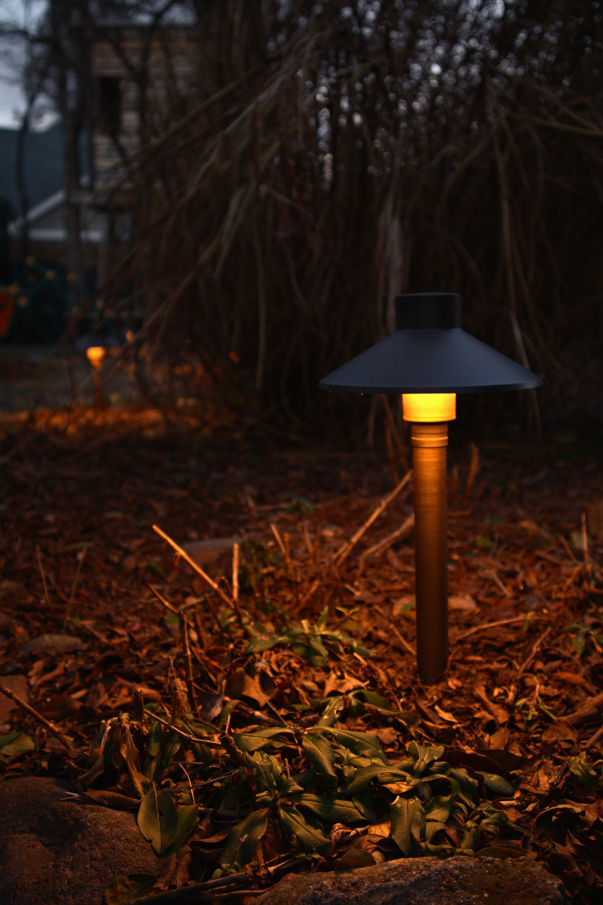 A close up image of a brass cast low-voltage landscape lighting fixutre.