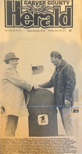 Vintage newspaper cover of 'Carver County Herald' featuring two men exchanging a letter at a U.S. mailbox, dated March 24, 1977 with Doug Hansen and the current mayor of Chanhassen.