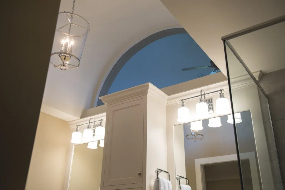 Bathroom with arch window, pendant lighting, and mirrored cabinets.