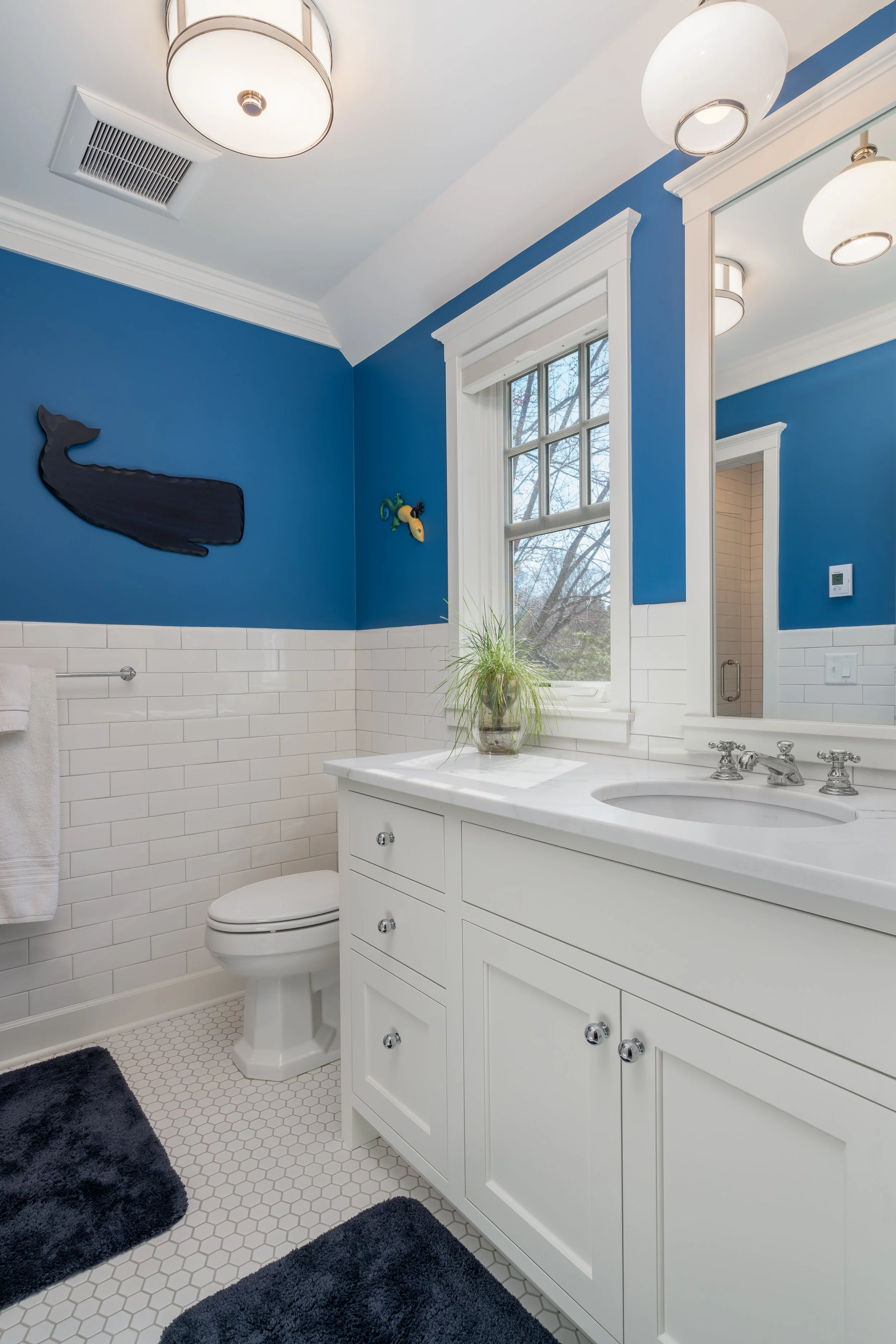 Modern bathroom remodel in Wayzata with blue walls, white vanity, and a decorative whale wall art.