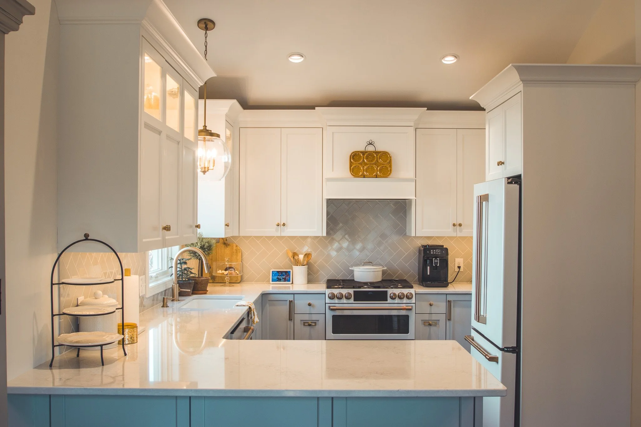 Modern kitchen with white cabinets, marble countertops, stainless steel appliances, and a central island.