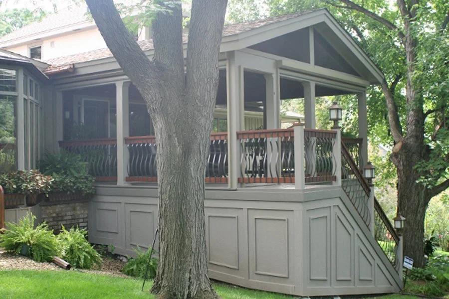 Covered porch remodel in Wayzata with wood railing and surrounding trees