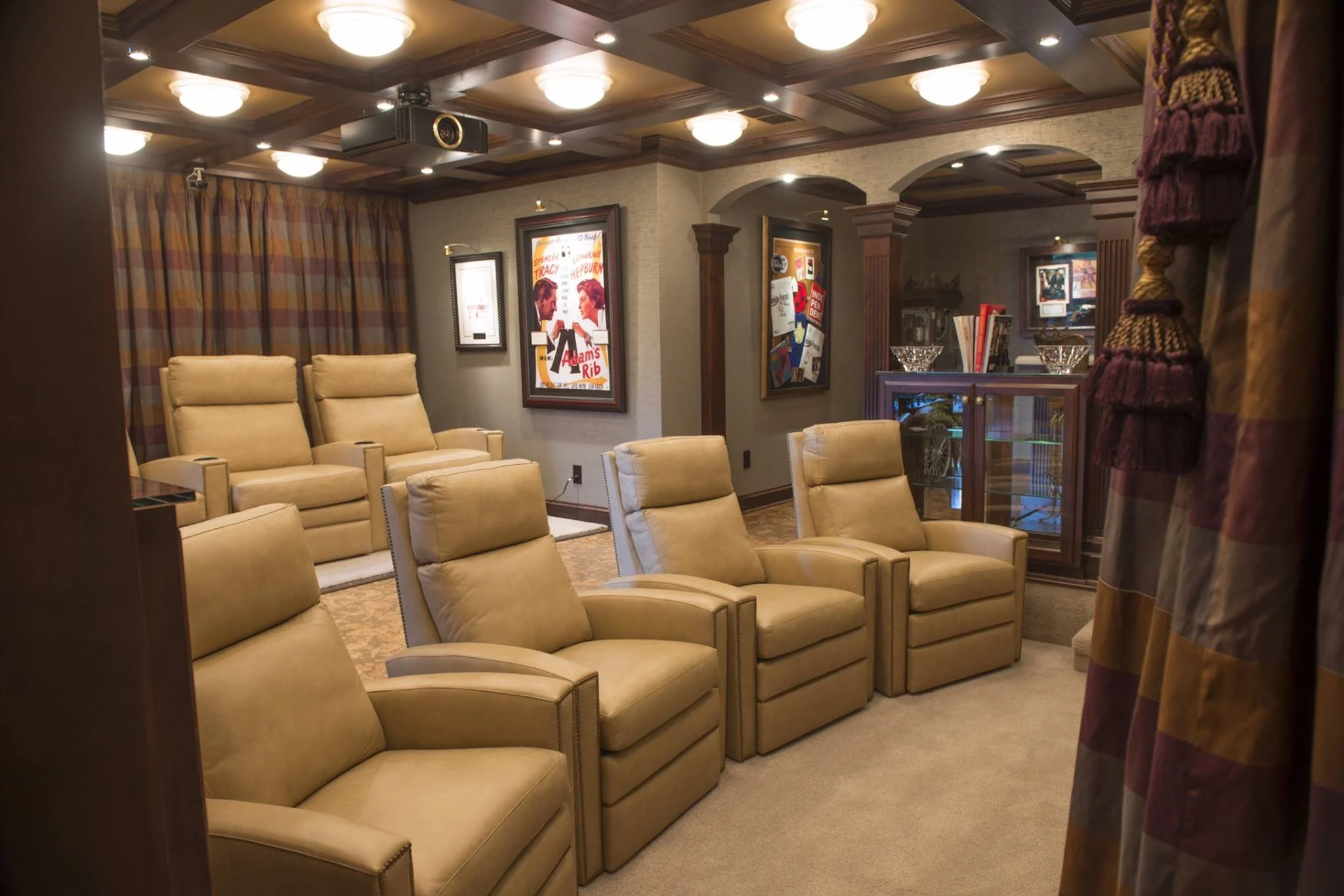 Home theater room remodel in Edina with leather recliner seating, movie posters on the walls, decorative curtains, and a ceiling-mounted projector.