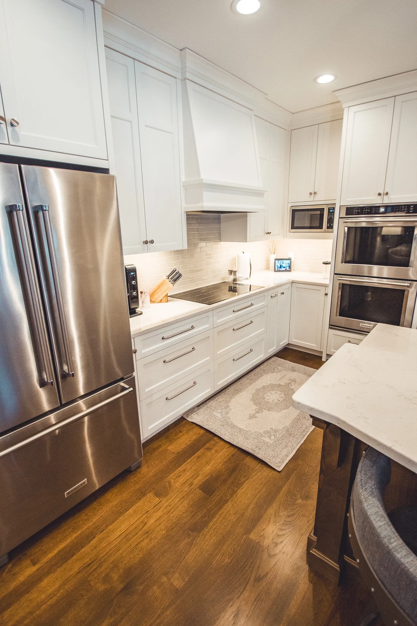 Modern kitchen remodel in Chanhassen with white cabinets, stainless steel appliances, and hardwood floor.