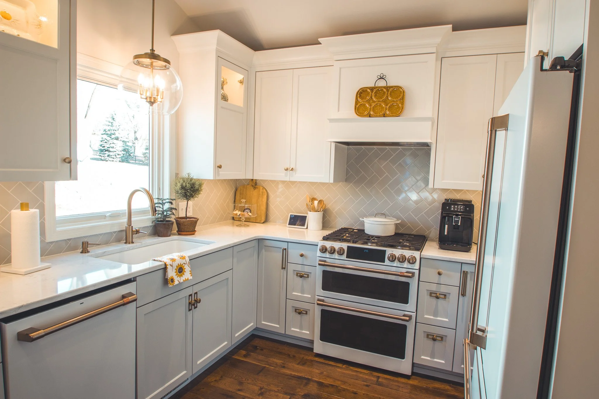 Modern kitchen remodel in Minnetonka with white cabinets, stainless steel appliances, farmhouse sink, and herringbone backsplash.