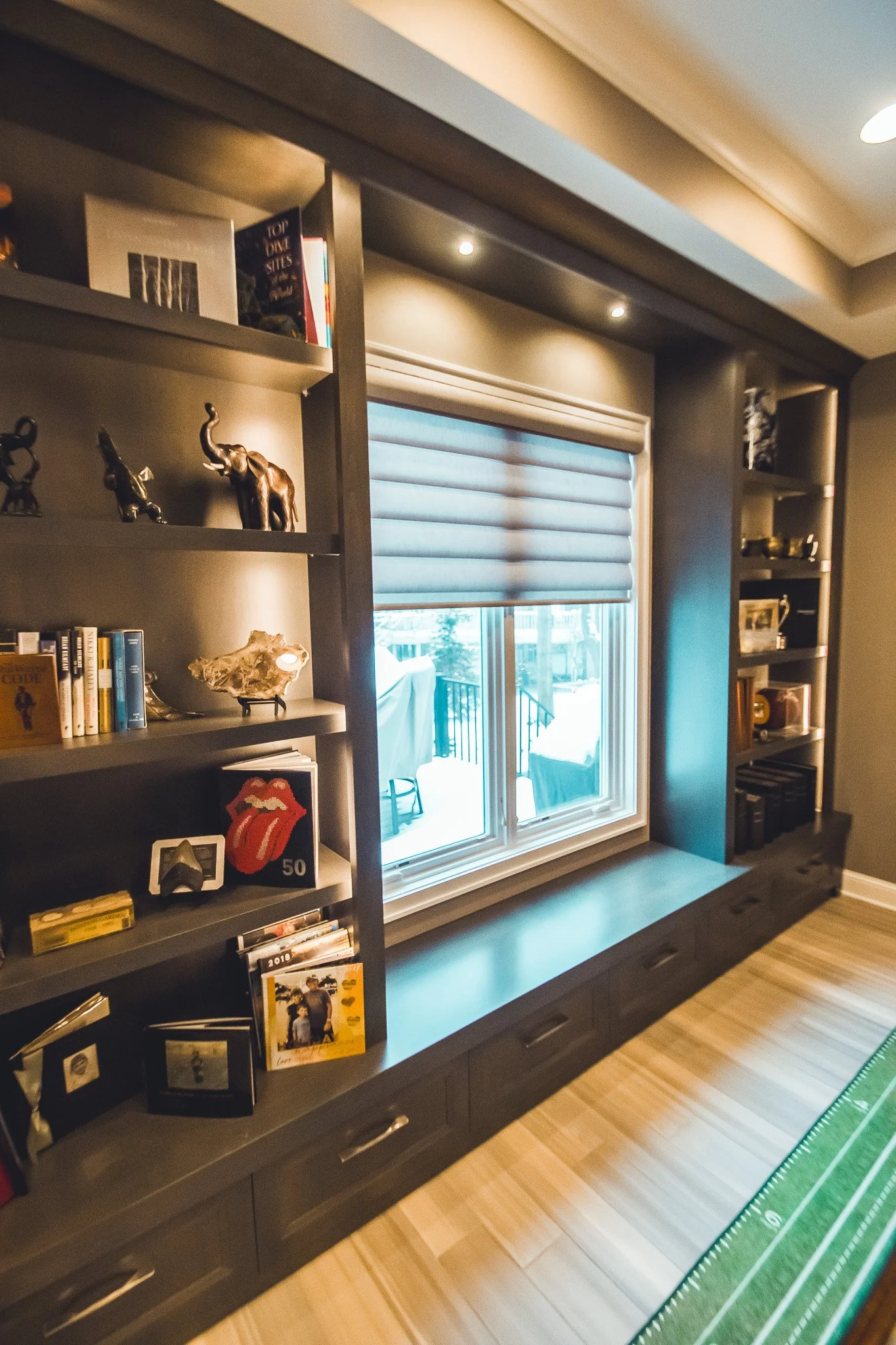 Modern home remodel in Minnetonka with a large built-in bookshelf surrounding a window. The shelves contain books, decorative items, and small sculptures.