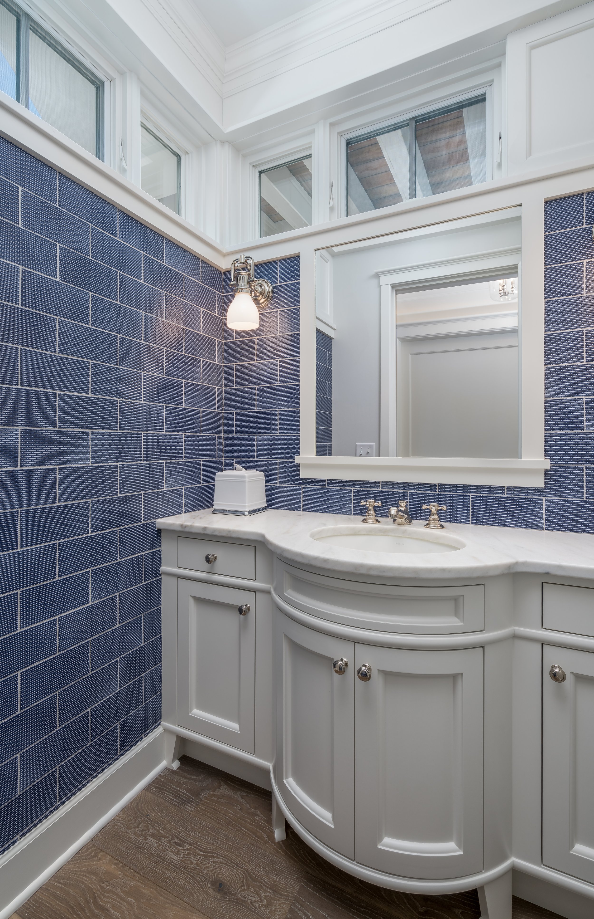 Bathroom remodel in Chanhassen with blue tiled walls, white vanity with marble countertop, mirror, and wall light.