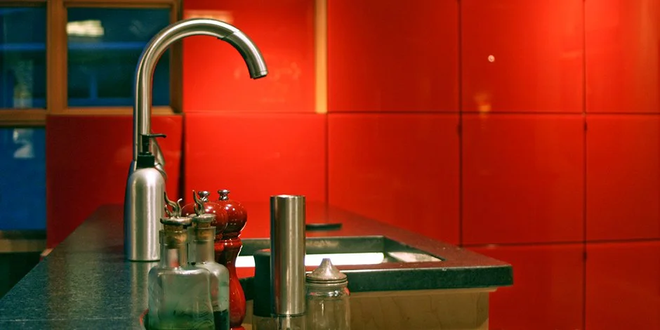 Modern kitchen in Minneapolis with red cabinets, sink, and various condiments on the counter