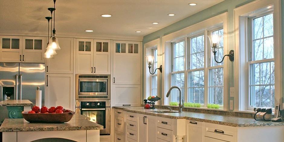 Modern kitchen in Victoria with white cabinetry, stainless steel appliances, pendant lights, granite countertops, and large windows.