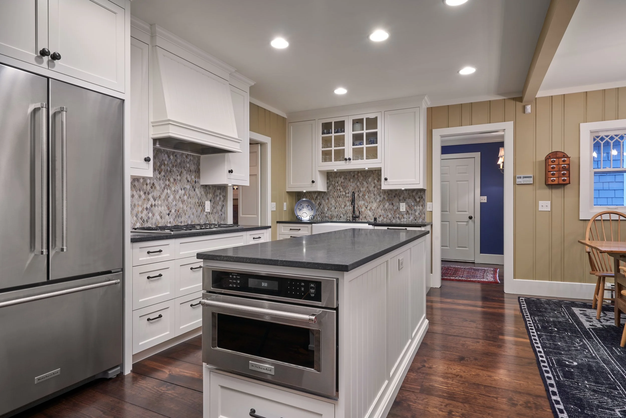 Modern kitchen in Chaska with white cabinets, stainless steel appliances, and a central island.