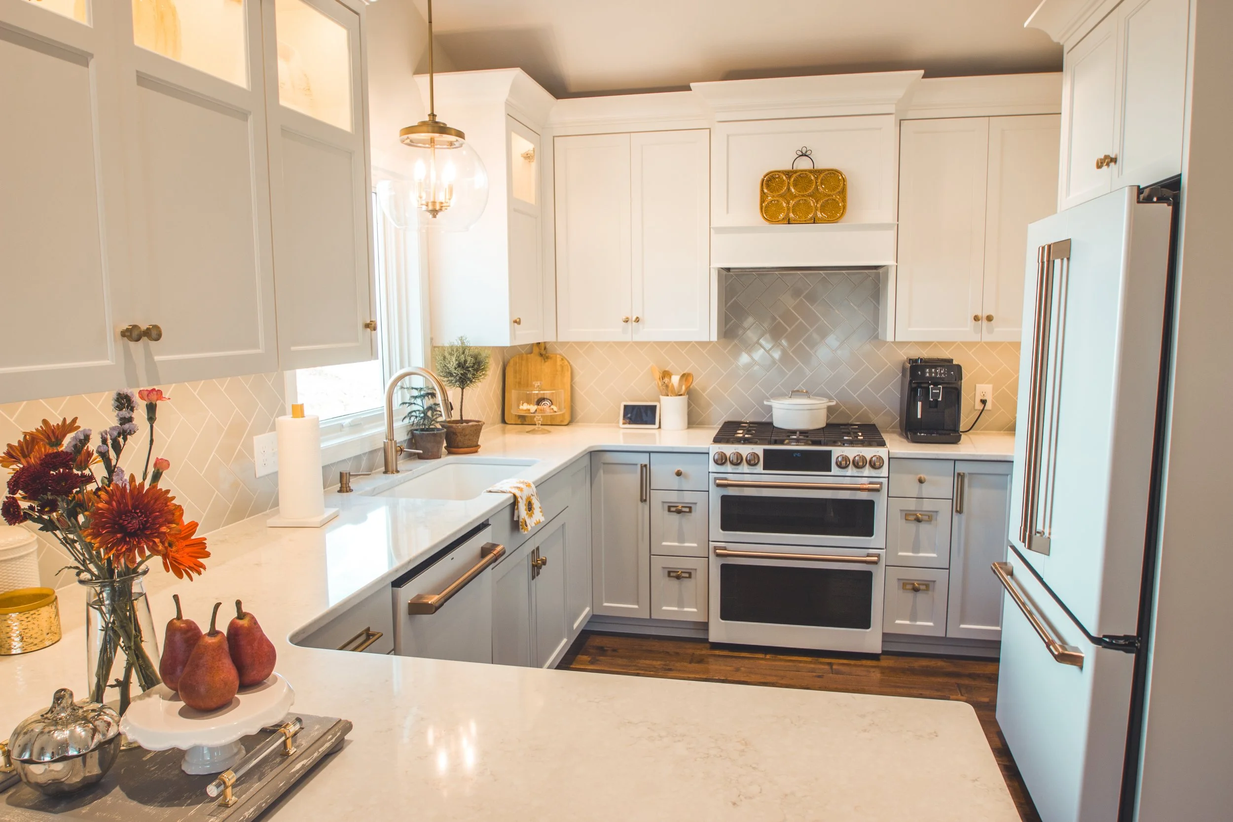Modern kitchen in Chanhassen with white cabinets, stainless steel stove, and a large sink. Decorative flowers and fruit on the countertop.