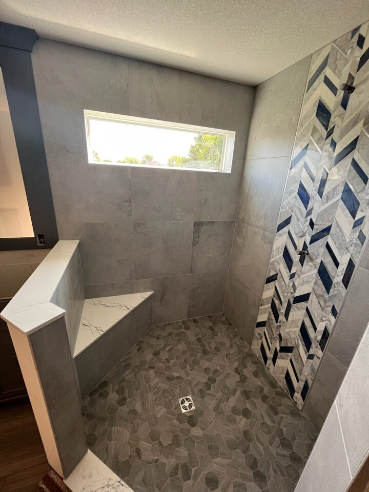 Modern shower remodel in Chanhassen with geometric tile design, gray tiles, and a built-in bench.