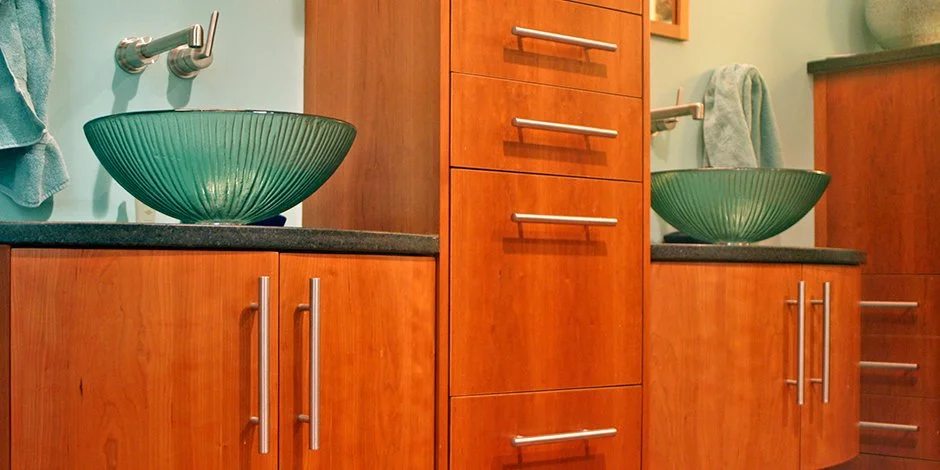 Modern bathroom remodel in Chanhassen with wooden cabinets and green glass vessel sinks.