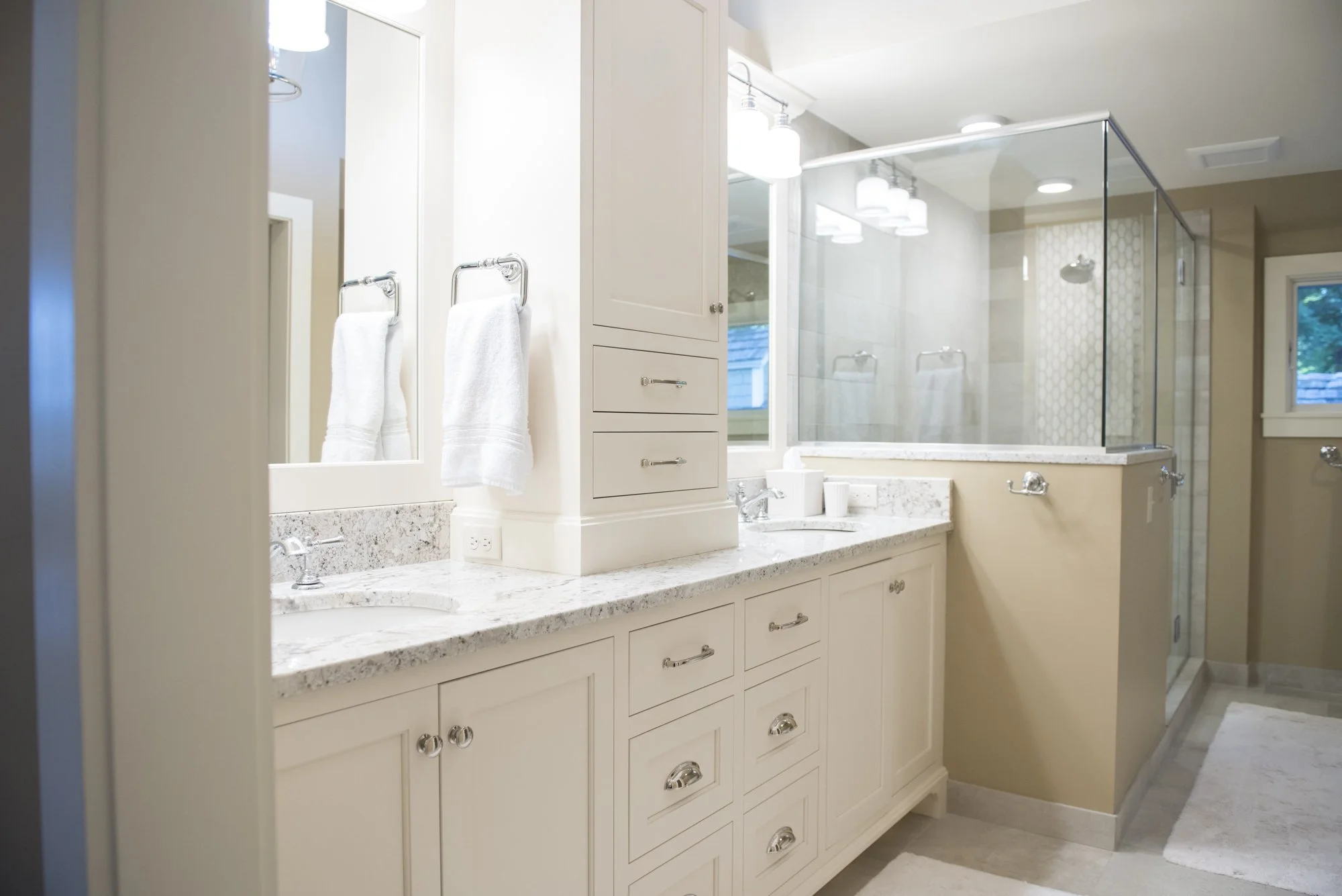 Modern bathroom  in Chanhassen with dual sinks, white cabinetry, granite countertops, glass shower enclosure, and towel racks.