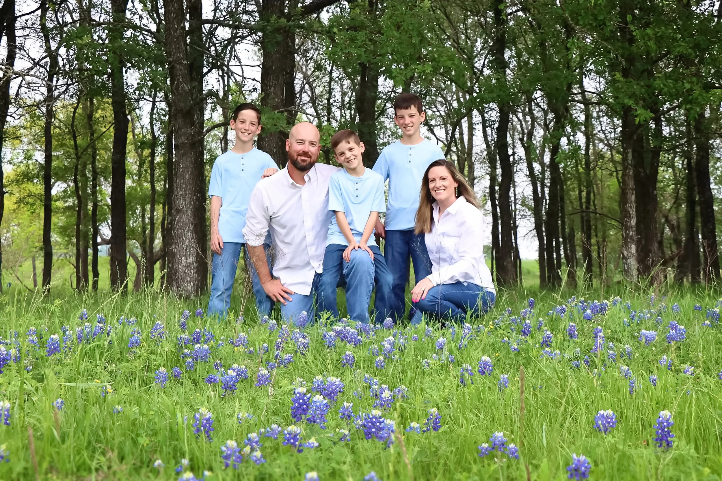 A family of five, including two adults and three children, poses outdoors in a bluebonnet field in the Belton area