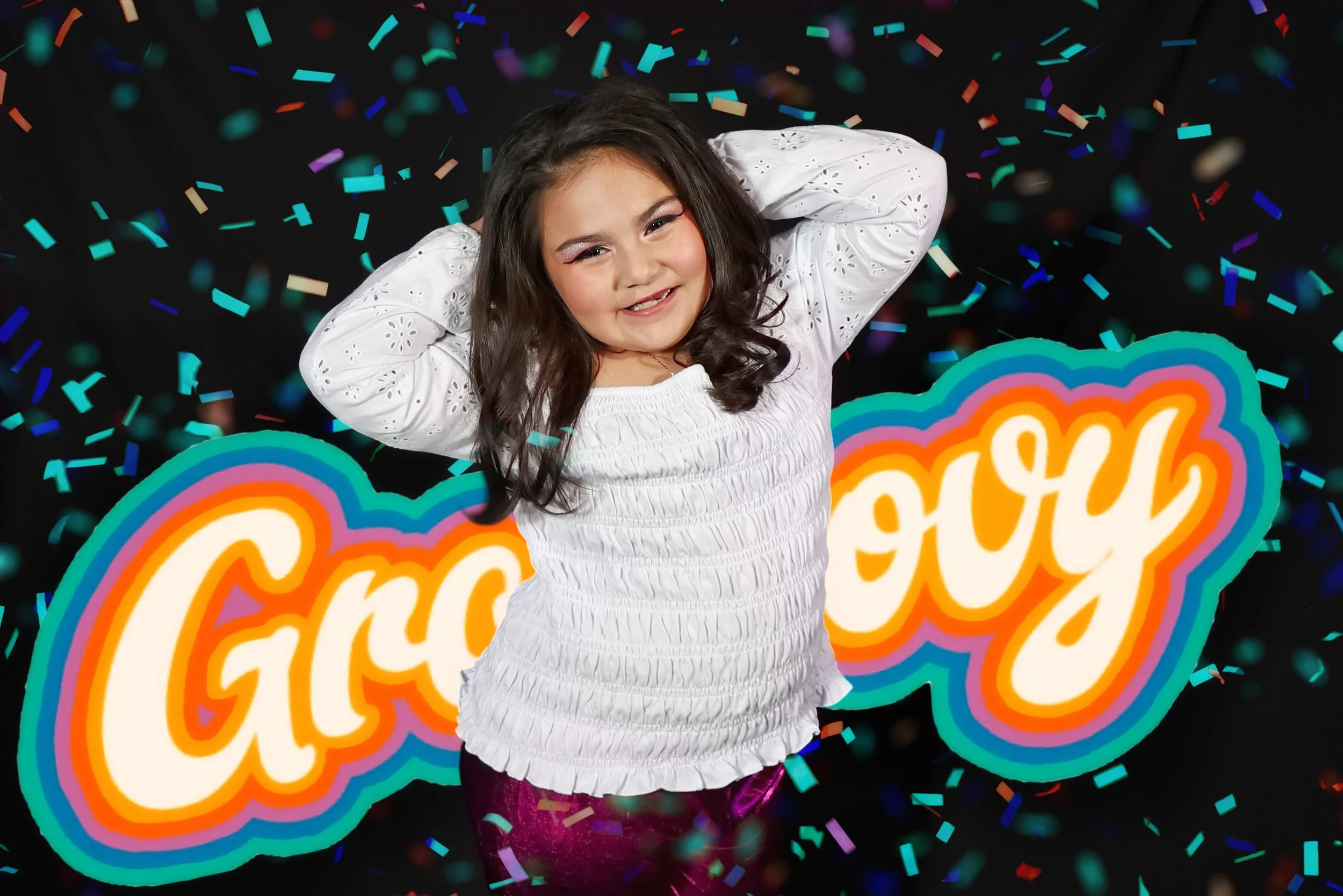 Young girl celebrating at a party with colorful confetti and a neon sign that says "Grow" in the background at Megan Gibson Photography studio in Belton, Texas.