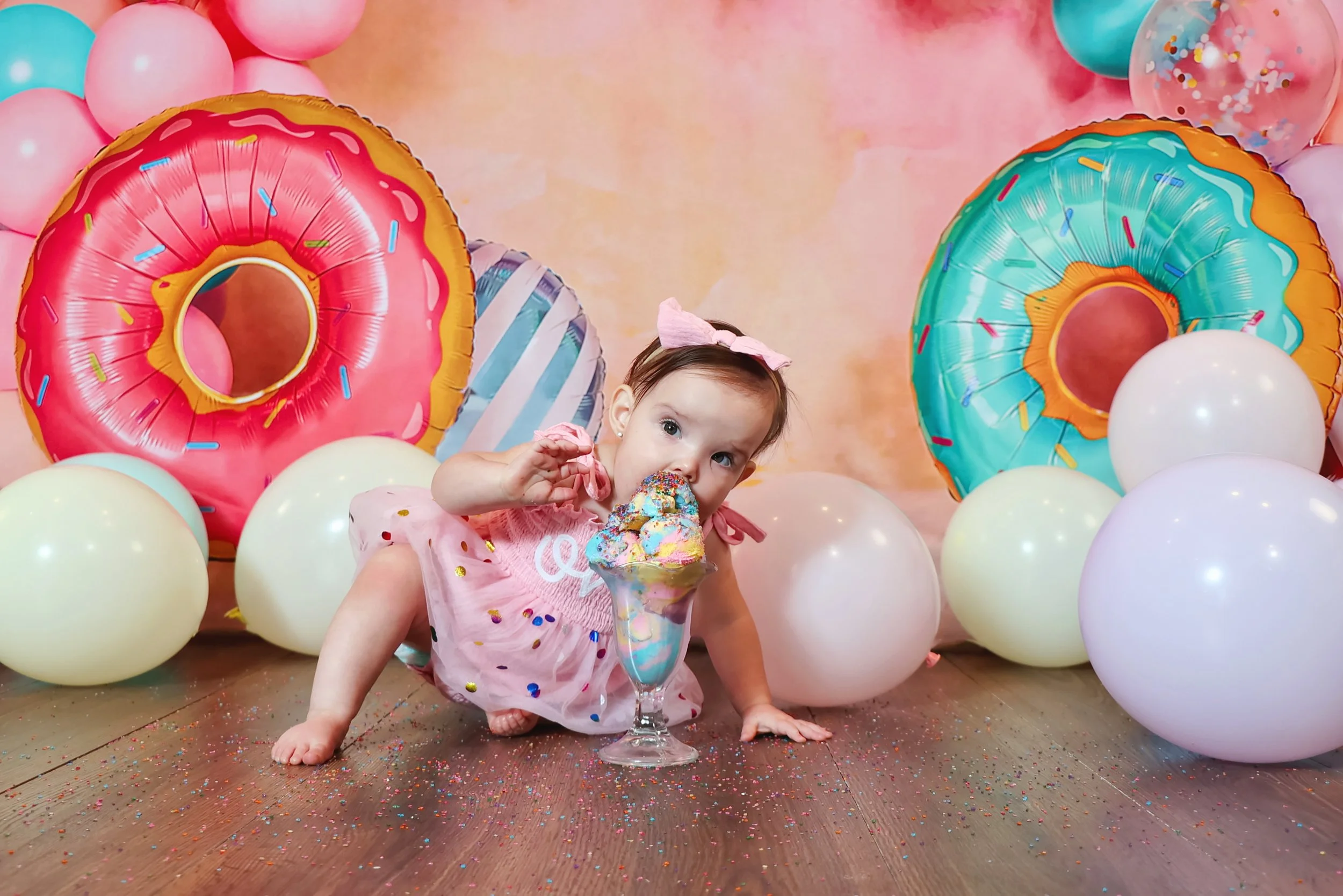 1 year old girl eating ice cream in a colorful and playful cake smash studio photography cake smash session