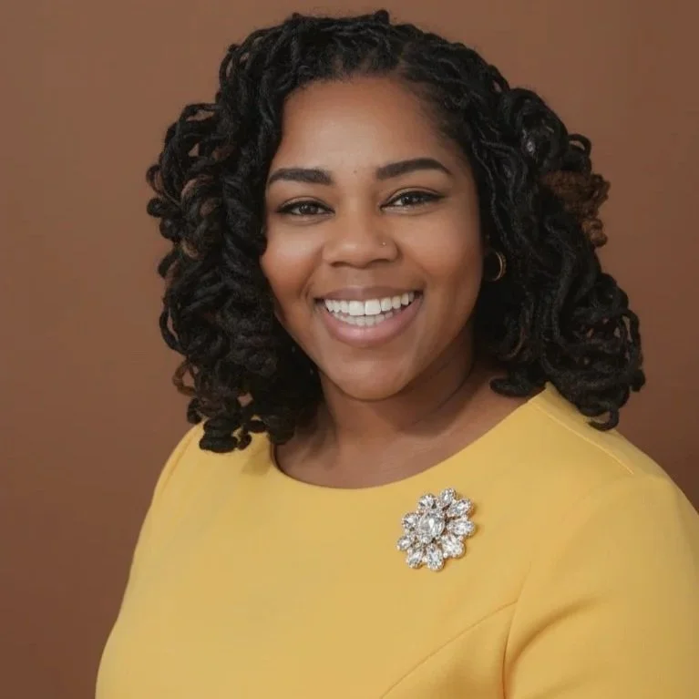 A woman with dark, curly hair and a bright smile, wearing a yellow top with a decorative brooch, standing against a plain brown background.
