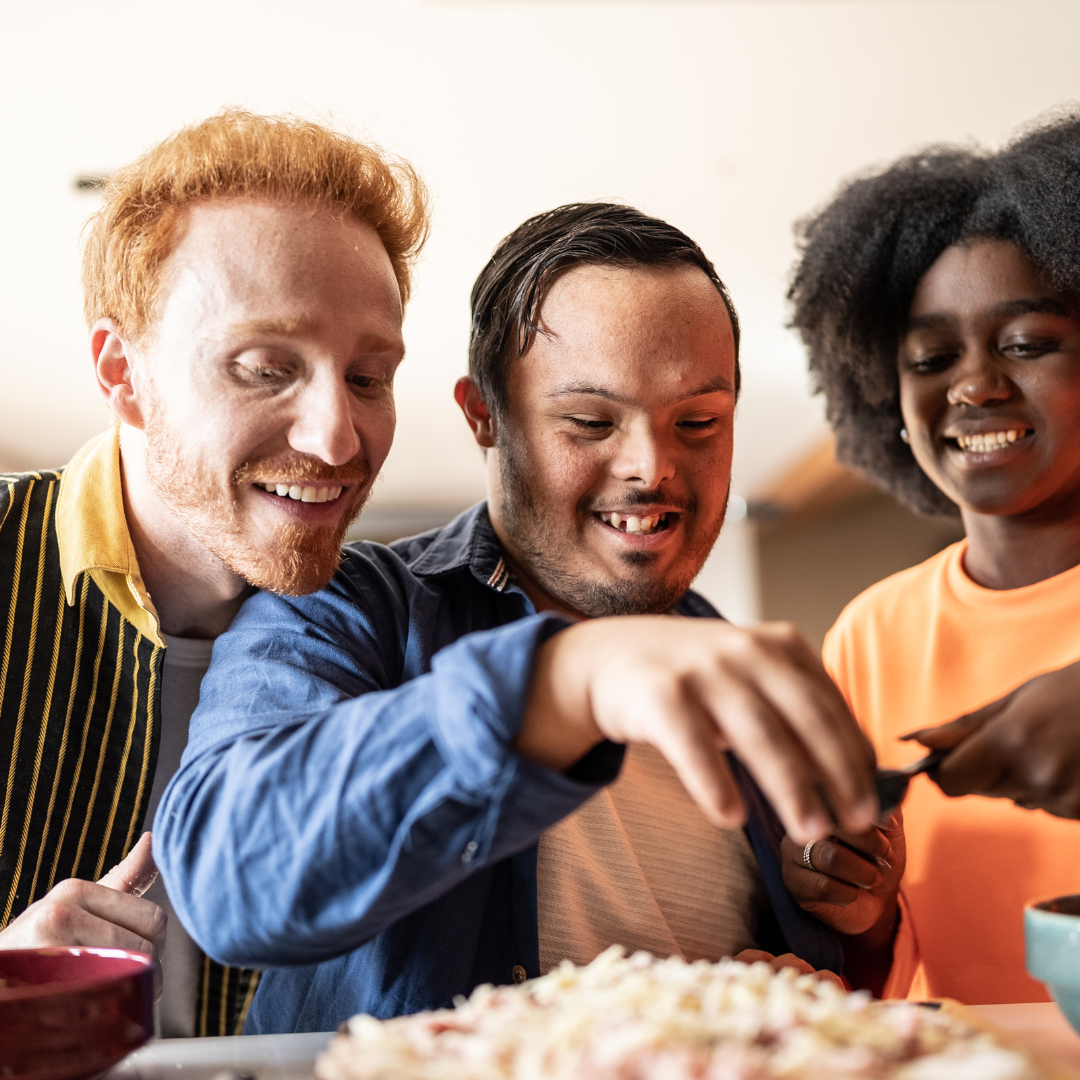 Three diverse people smiling and enjoying pizza together indoors.
