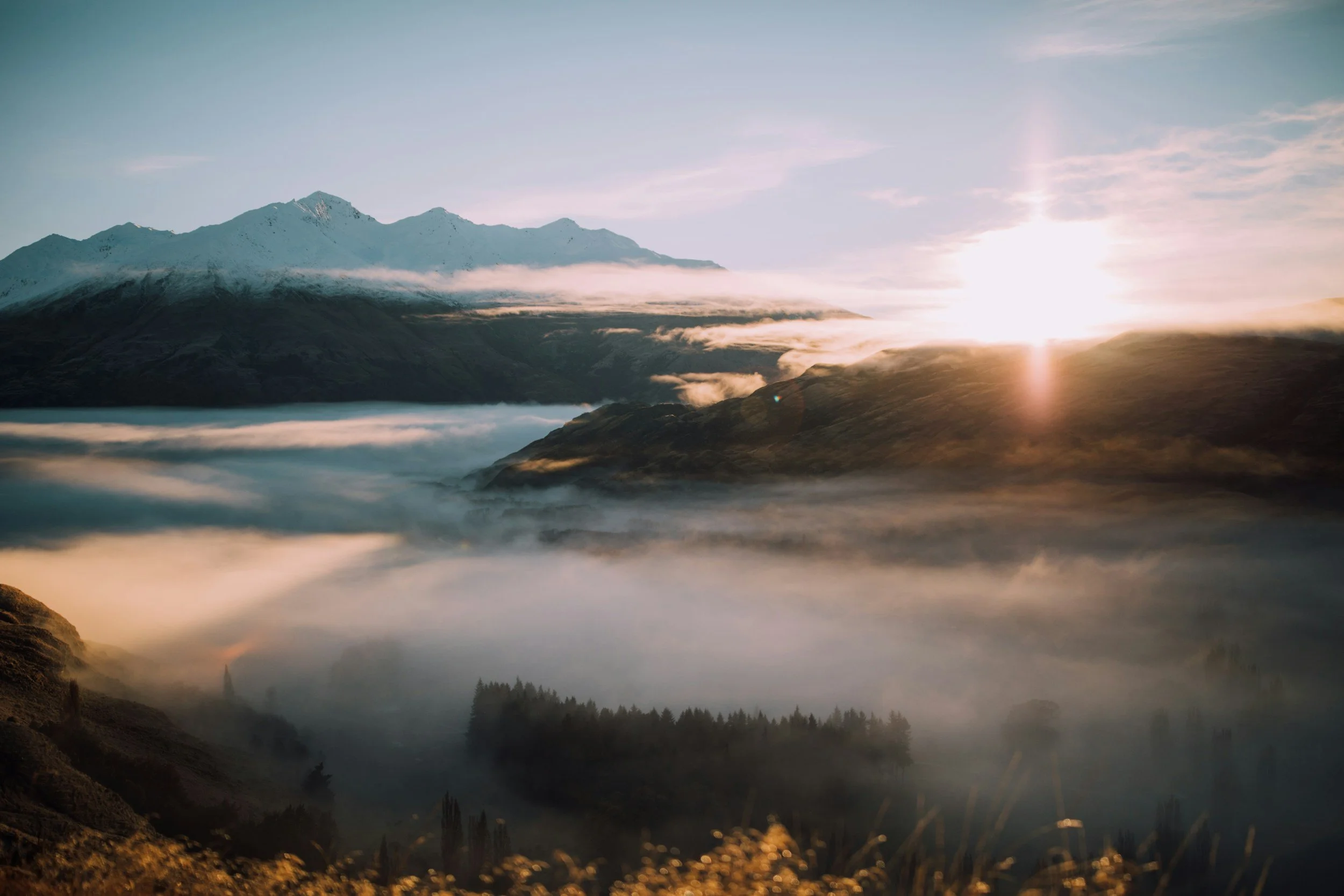 Sunrise over misty mountains with clouds and fog in a mountainous landscape.