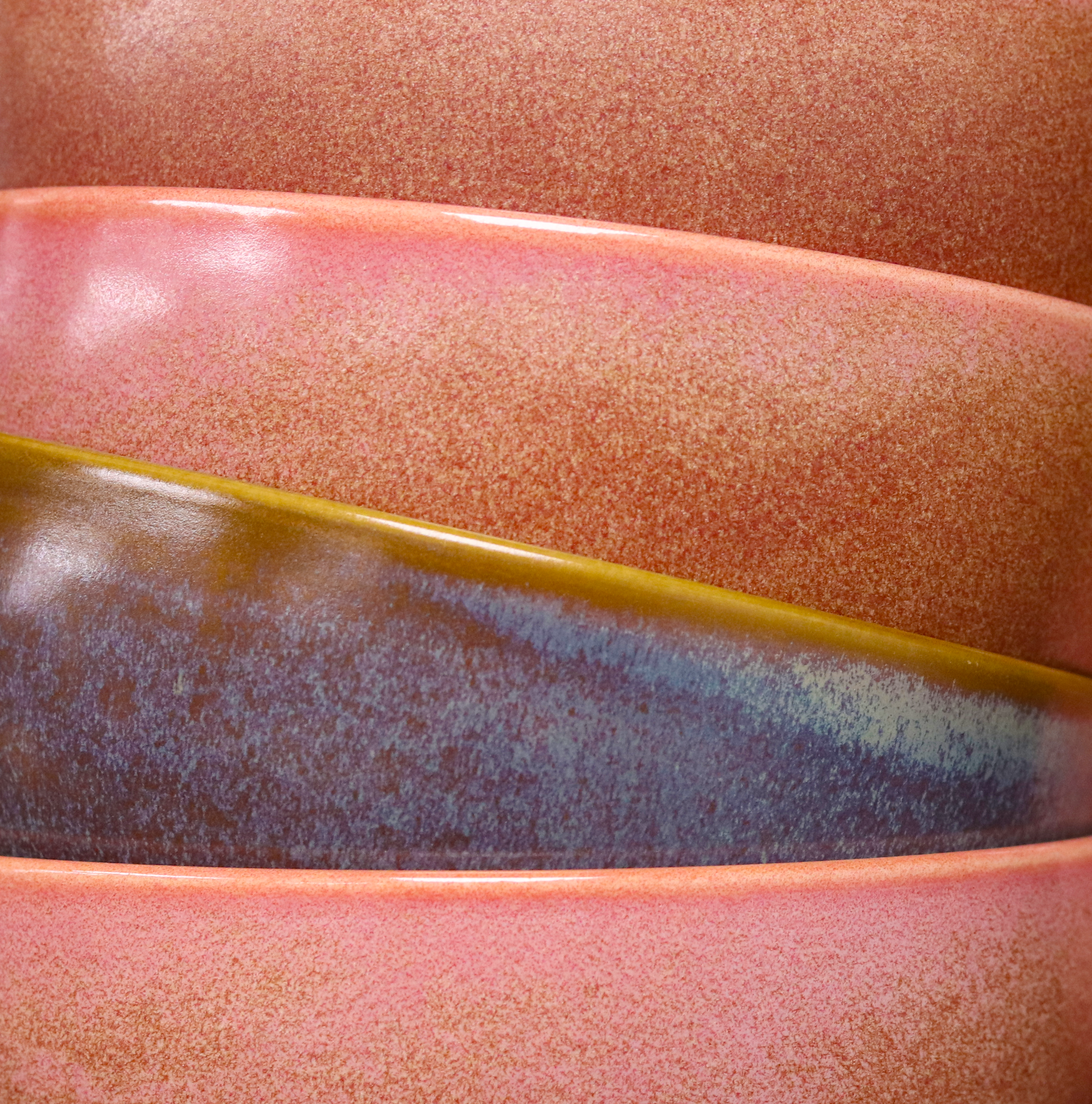 Close-up of textured, speckled stoneware or surface with a pink and reddish tone with each stacked on top of the other.