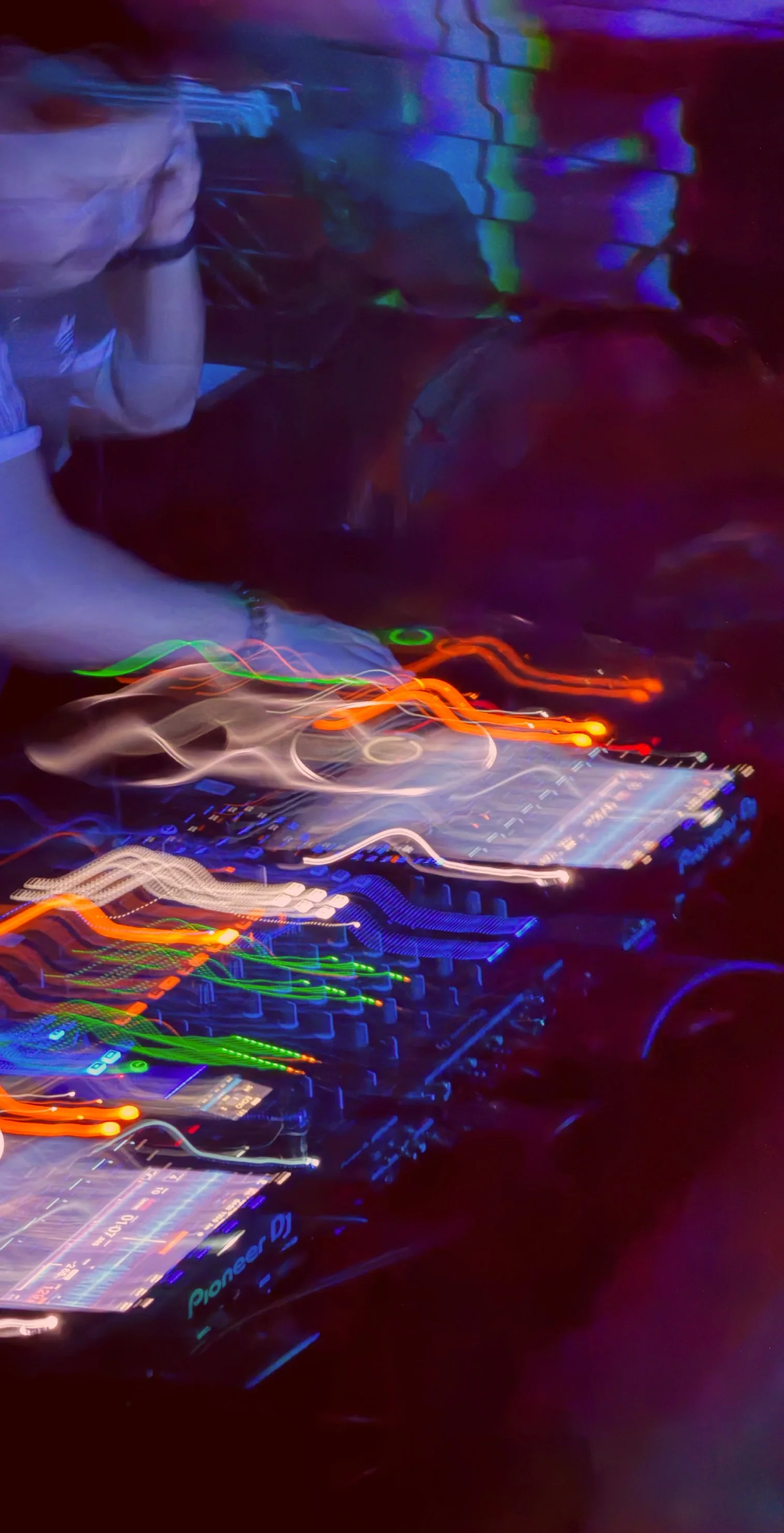 Light trails created by a DJ's equipment under colorful lighting at a nightclub or concert.