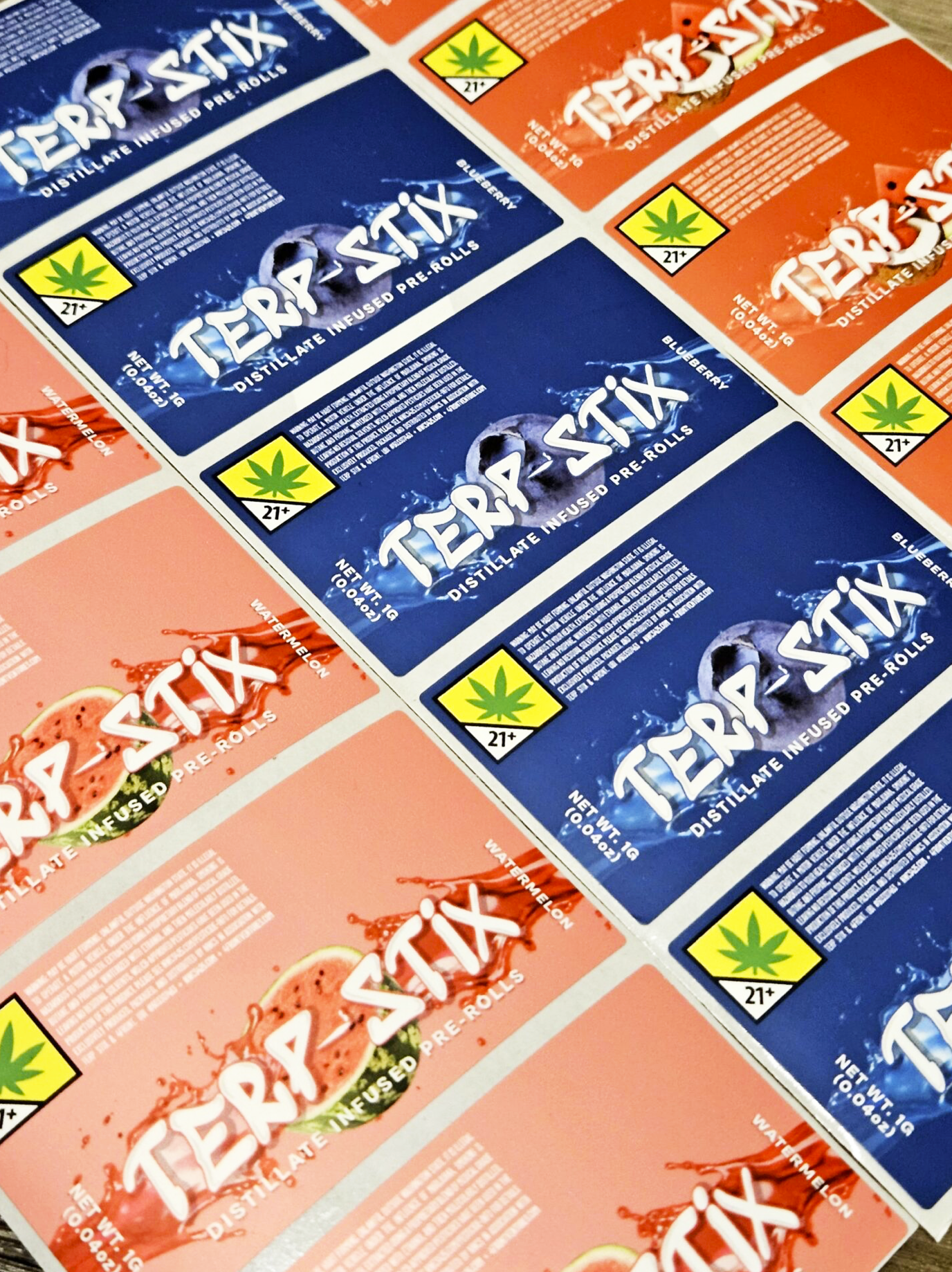 Multiple packages of Terp Stix cannabis-infused pre-rolls with flavor labels of blueberry and watermelon, featuring cannabis leaf symbols and age restriction icons.