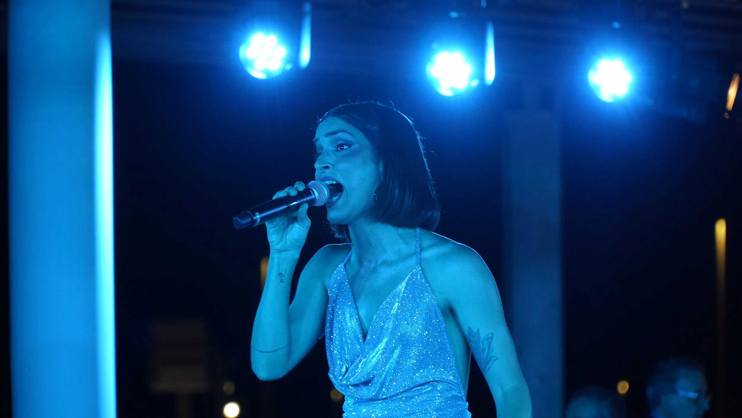 Cantante solista de Cuatr8chos actuando en directo en escenario con iluminación azul, ideal para eventos corporativos, galas y celebraciones con música en vivo.