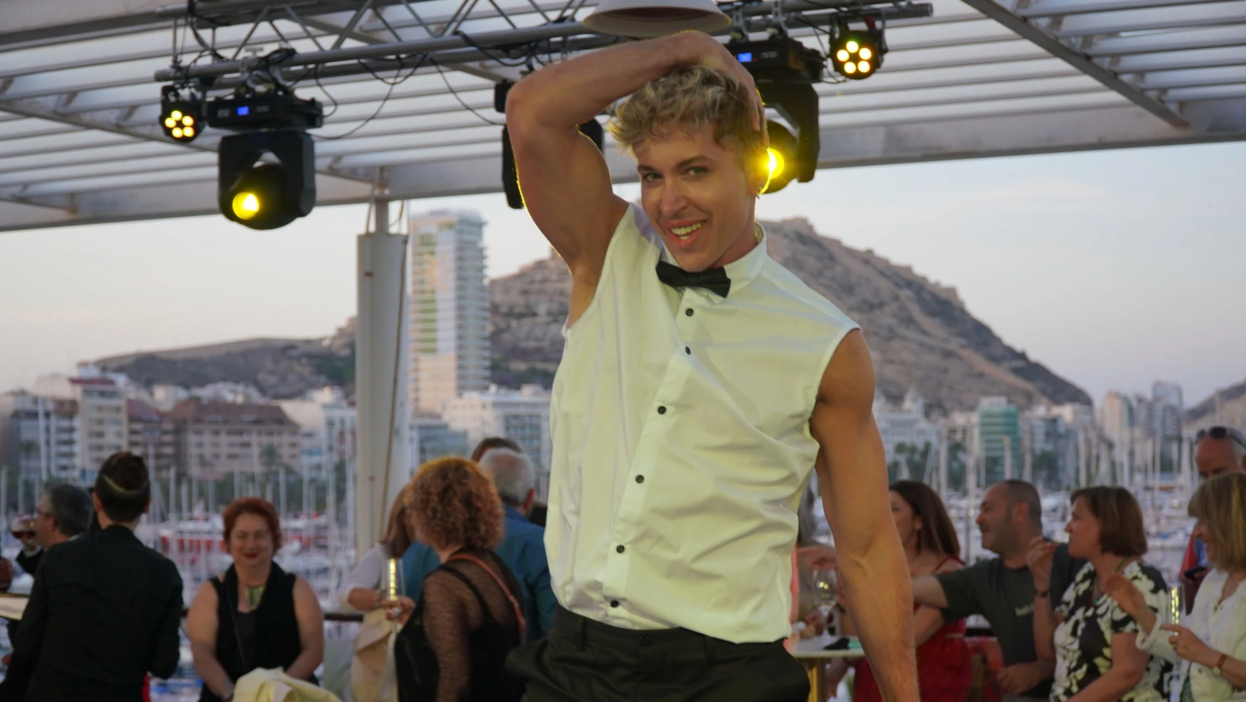 Bailarín de Cuatr8chos interactuando con los invitados en un evento en terraza, con coreografía informal y actitud dinámica durante una celebración al atardecer.