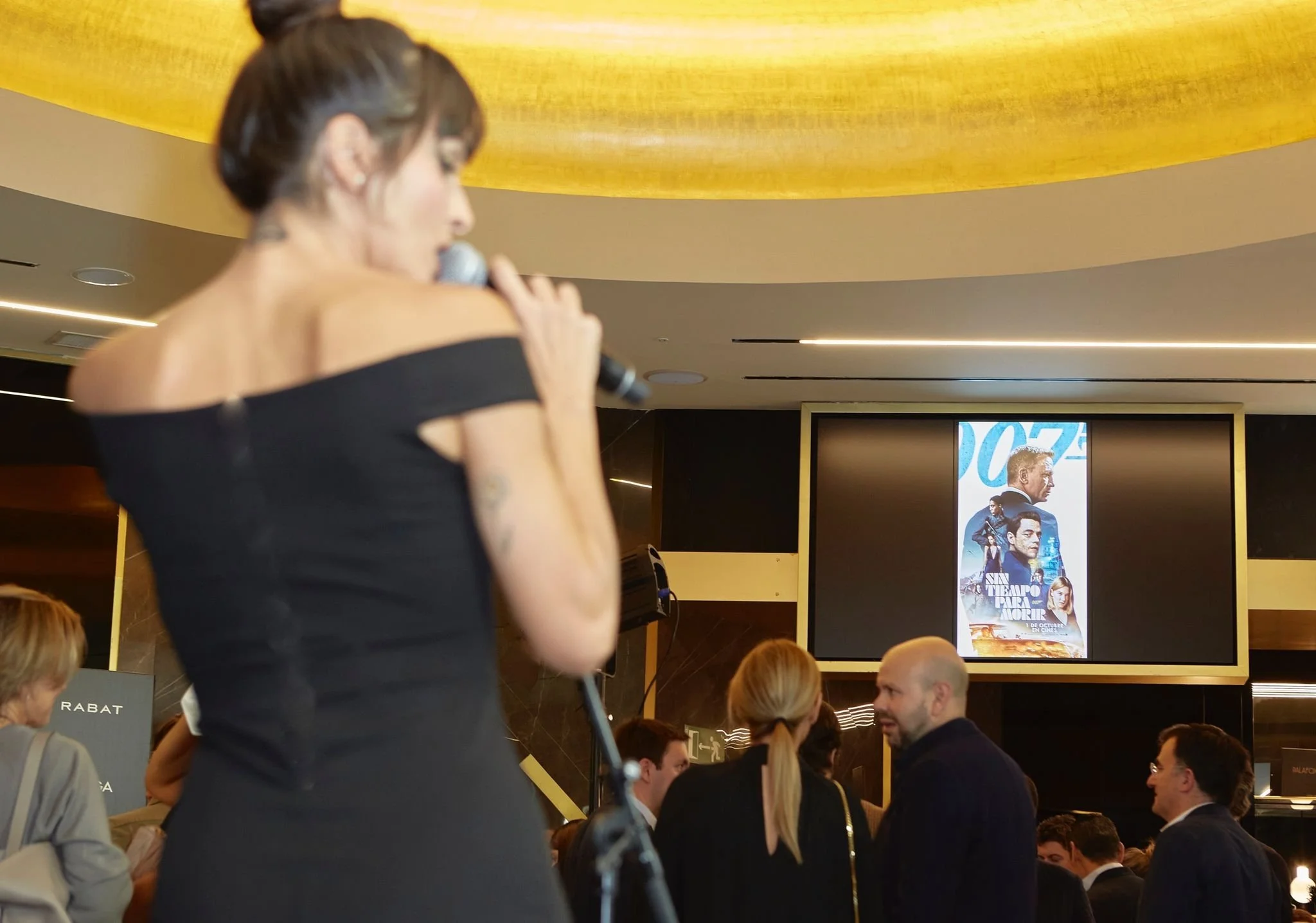 Mujer con cabello oscuro y vestido negro cantando en un micrófono en un evento
