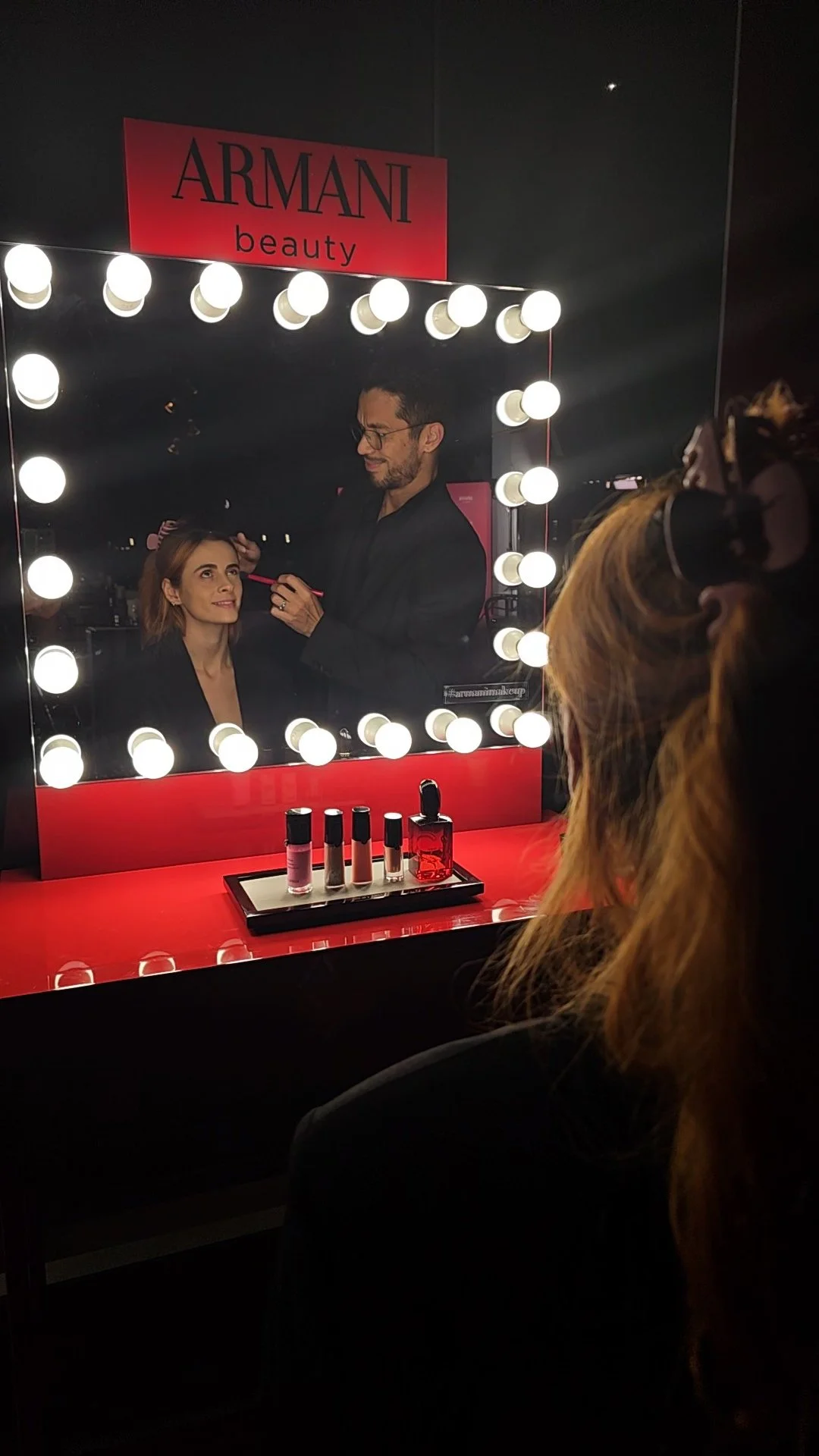 Preparación de maquillaje backstage para una activación de marca de Armani Passion, con performers de Cuatr8chos listos para una presentación de producto en evento.