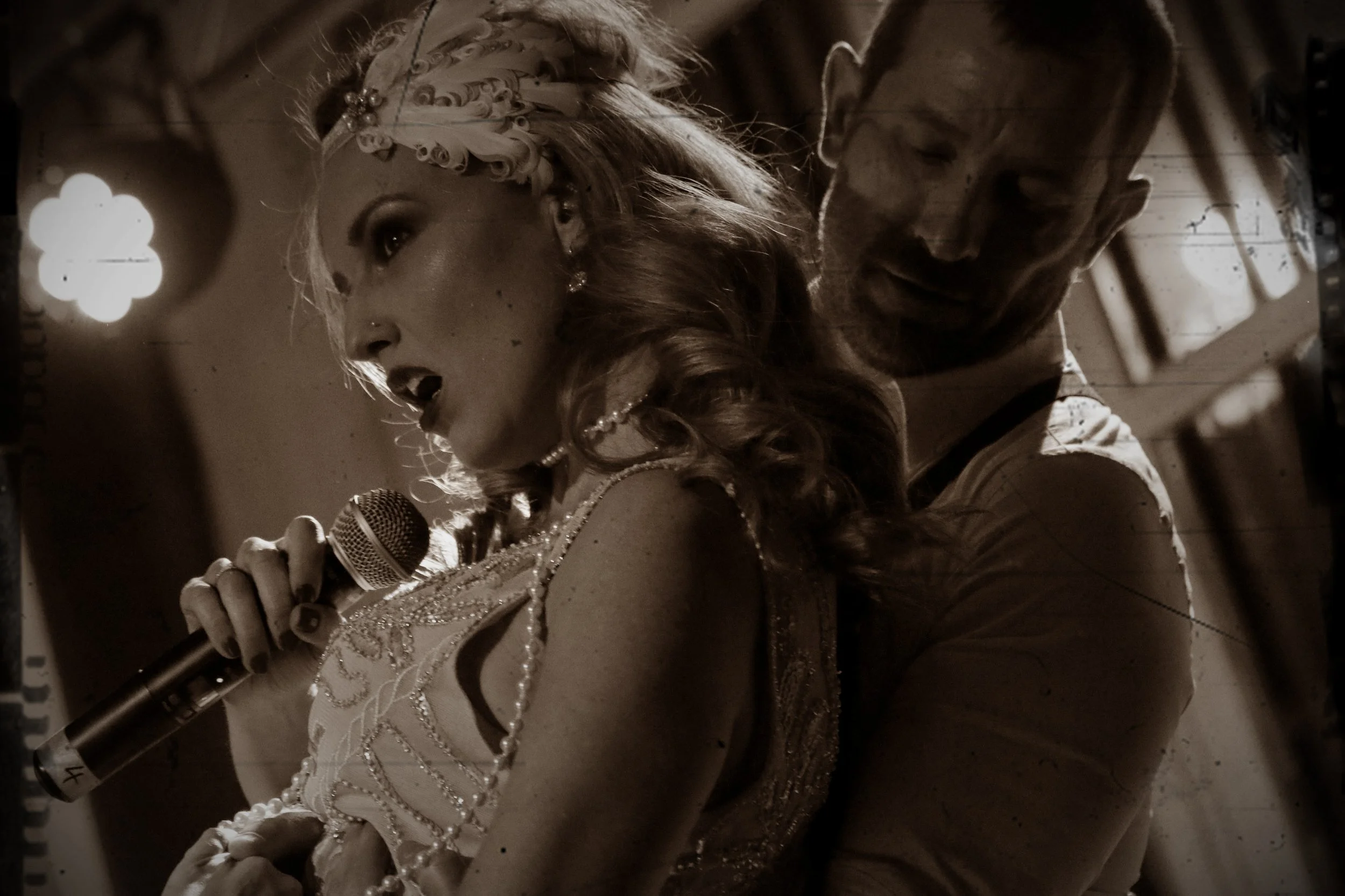 Momento escénico de un show en vivo, con cantante principal acompañada por otro intérprete, en una puesta en escena elegante con iluminación cálida.