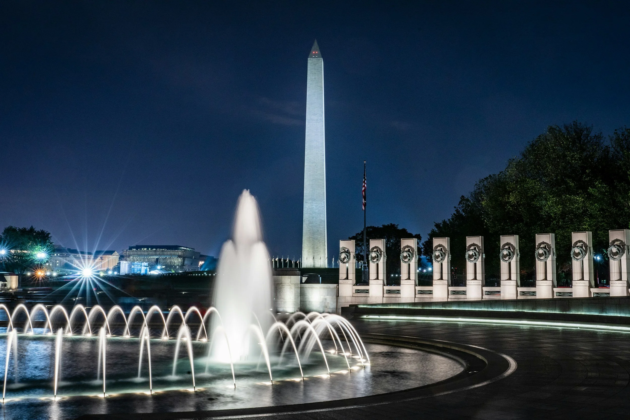 Fountain at the Vietnam Memorial at night time with a view of the Washington Monument in the background