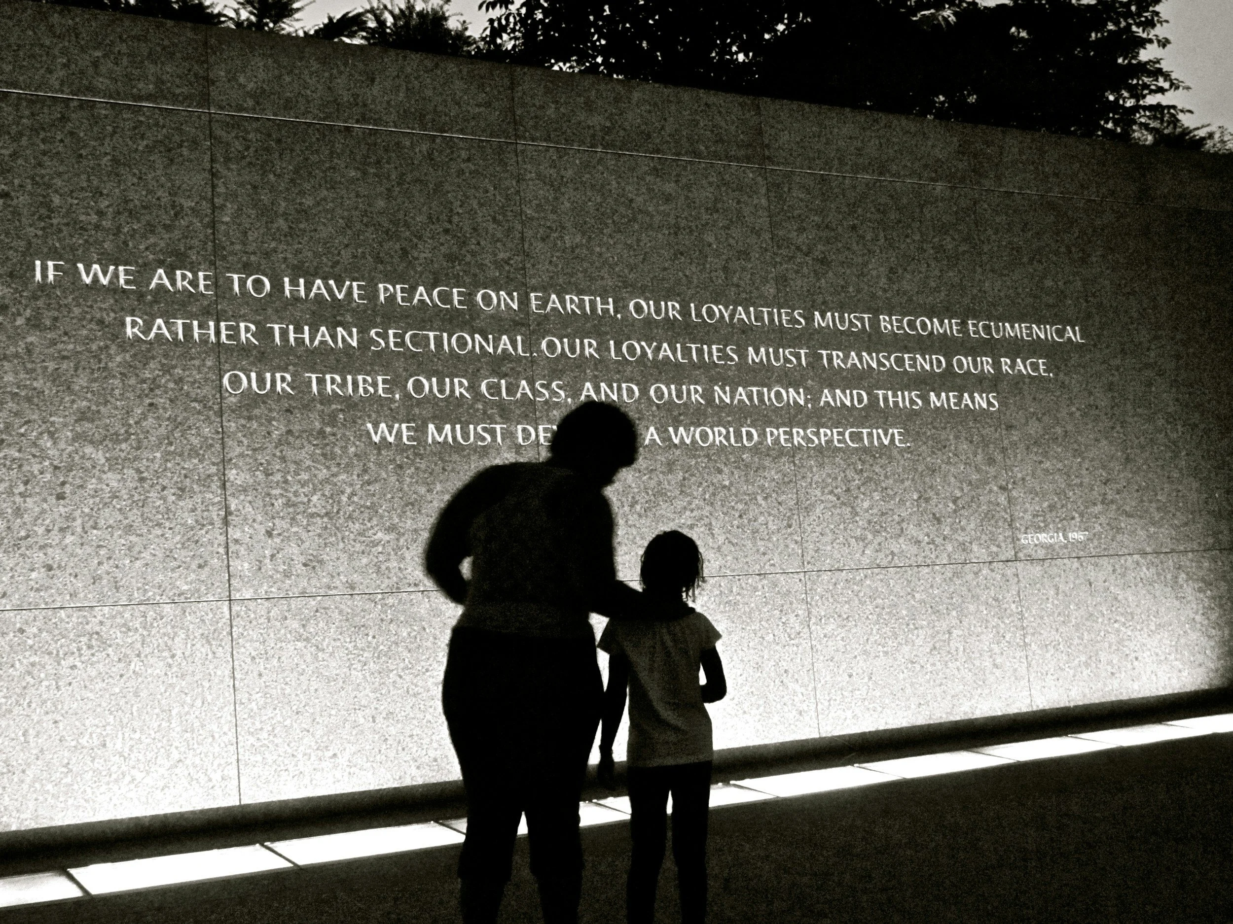 A family admires the WWII Memorial at night time in Washington, DC.