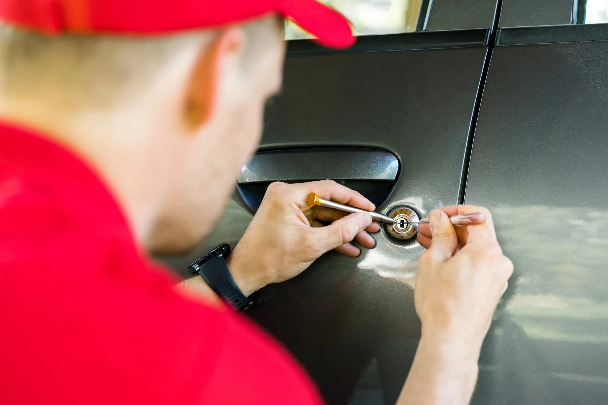A person changing a car's door lock using a screwdriver, with the car door and lock visible.